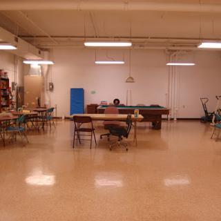 An empty art studio featuring several tables and chairs, illuminated by overhead lighting.