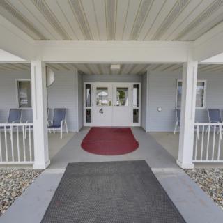A covered entrance to a building with a red carpet and seating area.