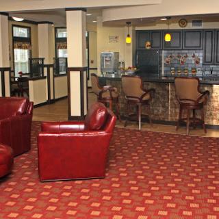 A cozy lobby area featuring red leather chairs and a bar counter, perfect for relaxing.