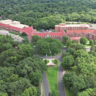 Aerial view of a college campus surrounded by lush greenery.