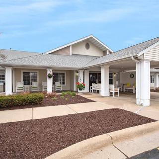 A residential-style building with a covered entrance and a landscaped front yard.