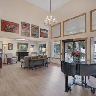 A spacious living room with a grand piano, stylish furniture, and elegant lighting.