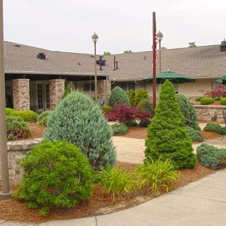 A well-maintained garden with various shrubs and plants in front of a building.