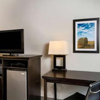 A cozy hotel room featuring a desk, lamp, and a TV.
