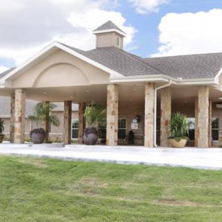 A large building with columns and a spacious lawn.