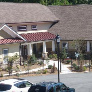 A suburban residential building with a fenced front yard and parked cars.