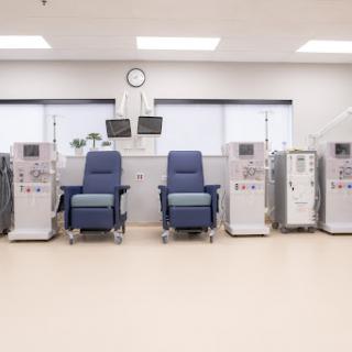 A clean and organized dialysis treatment area featuring multiple medical chairs and equipment.