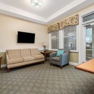 A comfortable living room featuring a sofa, armchair, wall-mounted television, and a small table.