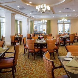 An elegant dining area with neatly arranged tables and chairs, featuring chandeliers and place settings.