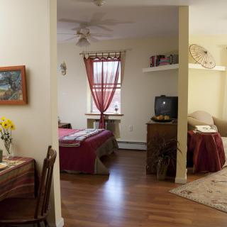 A cozy apartment interior featuring an open living and bedroom area with simple, warm decor.