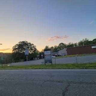 A peaceful scene at sunset, showcasing a view of a quiet road alongside buildings and trees.