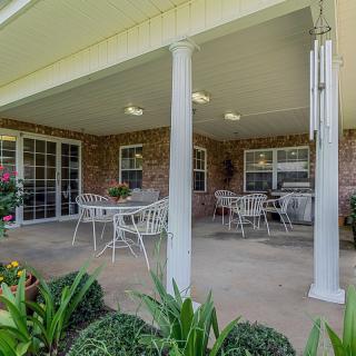 A cozy covered patio with outdoor furniture and garden views.