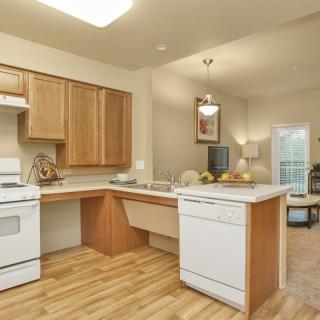 A cozy kitchen with wooden cabinets and a range of appliances, including an oven and dishwasher.