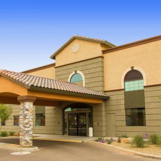 The image shows the entrance of a modern medical facility with arched windows and a covered walkway.