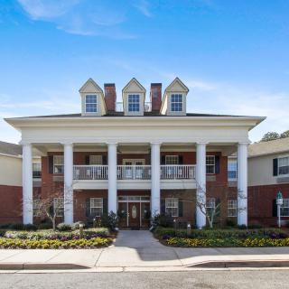 A two-story residential building with prominent columns and brick exterior under a clear blue sky.