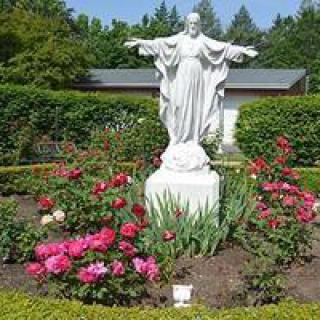 A statue in a garden surrounded by vibrant flowers.