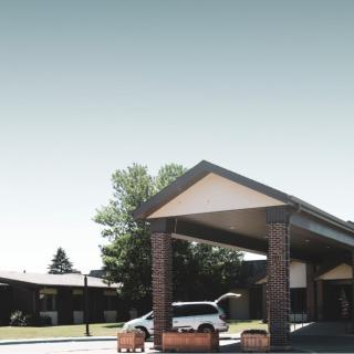 A car parked under a modern carport with trees in the background.
