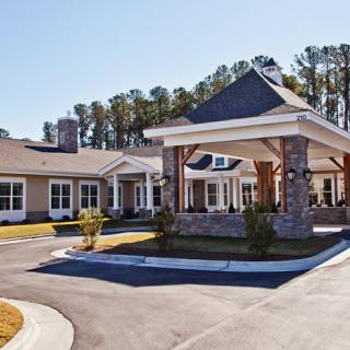 A modern building with a covered entrance and landscaped surroundings.