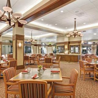 A spacious and elegantly designed dining area with wooden furniture and chandeliers.