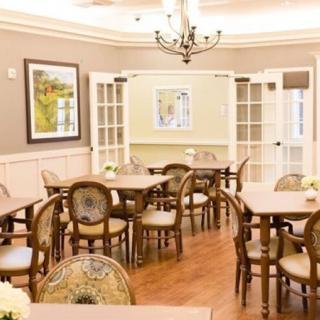 A warmly lit dining area with elegant furniture and artwork on the walls.