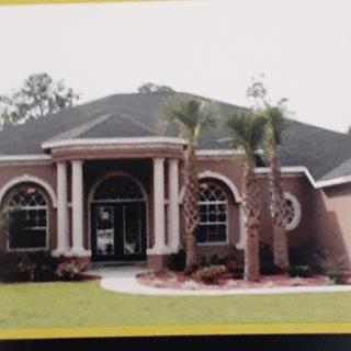 A suburban house with a manicured lawn and palm trees in the front yard.
