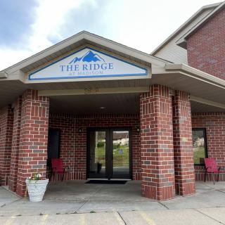 Entrance of a brick building with an awning and two chairs.