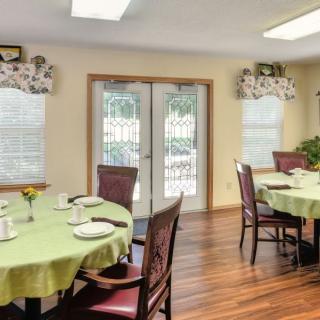 A cozy dining room with set tables and wooden flooring.