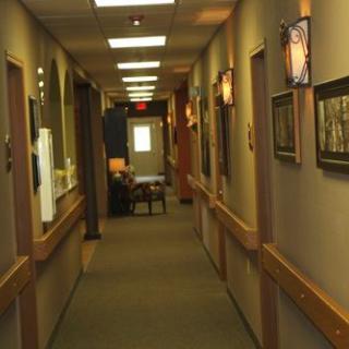 A well-lit office hallway with carpet flooring and multiple doors on both sides.