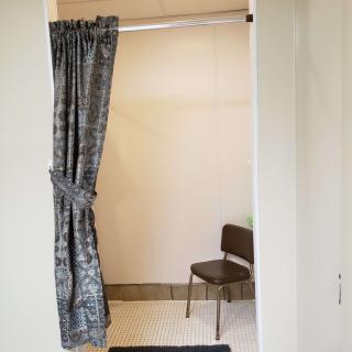 A fitting room with a partially open curtain and a chair inside.
