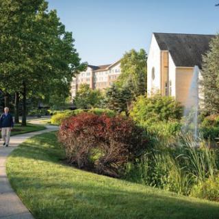 A peaceful pathway surrounded by lush greenery and modern residential buildings, inviting leisurely strolls.