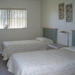 A minimalist bedroom featuring two twin beds with simple decor and a window allowing natural light.