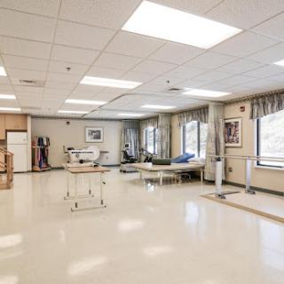 A spacious and well-lit medical room designed for rehabilitation, featuring various equipment and a calming environment.