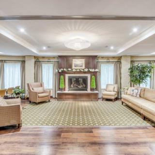 A spacious living room with a fireplace, elegant furniture, and a chandelier.