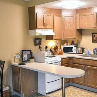 A cozy kitchen with wooden cabinets and a countertop, featuring a stove and microwave.