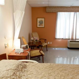 A hospital room with a bed, chairs, and medical equipment.