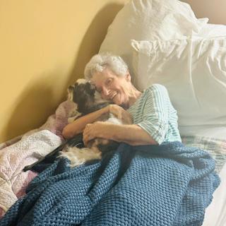 An elderly woman enjoying a cozy moment with her beloved dog in bed.
