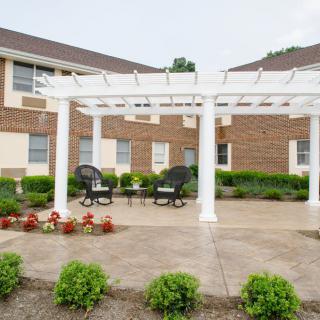 A patio area with a white pergola and outdoor seating in a garden setting.