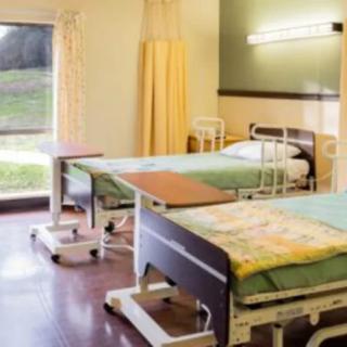 A hospital room with two neatly arranged beds and medical equipment.