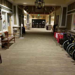 A well-lit hallway featuring seating and wheelchairs along the sides.