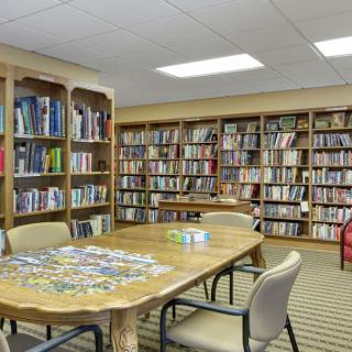 A quiet library room with shelves full of books and a table surrounded by chairs.