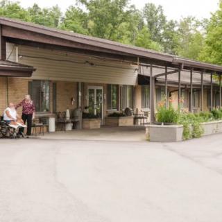 People sitting outside a building with a patio surrounded by trees.