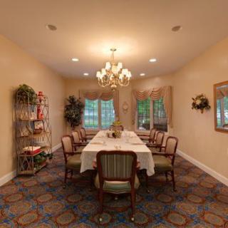 A cozy dining room with a central table, elegant chairs, and a chandelier.