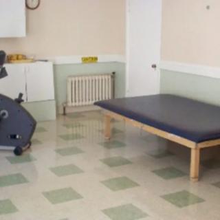 A physical therapy room with an exercise bike and a mat.
