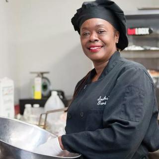 A chef smiling while holding a bowl in the kitchen.