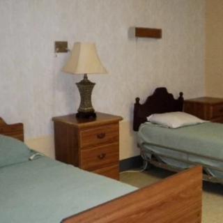 A simple bedroom with two single beds, nightstands, and a lamp.