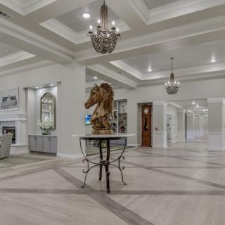 A luxurious lobby area featuring elegant chandeliers, a central sculpture on a table, and sophisticated ceiling designs.