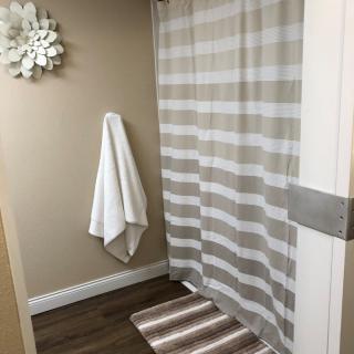 A cozy bathroom with a striped shower curtain and matching bath mat.