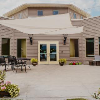A modern outdoor patio area with furniture and an awning in front of a building.