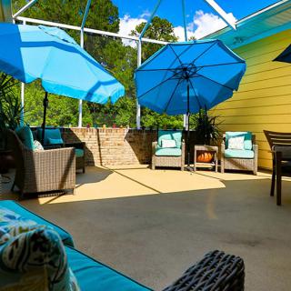 A sunny patio with blue umbrellas and comfortable seating.