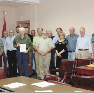A group of people gathered in an office setting, with one person holding a certificate.